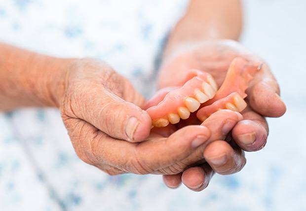 Someone holding a set of dentures