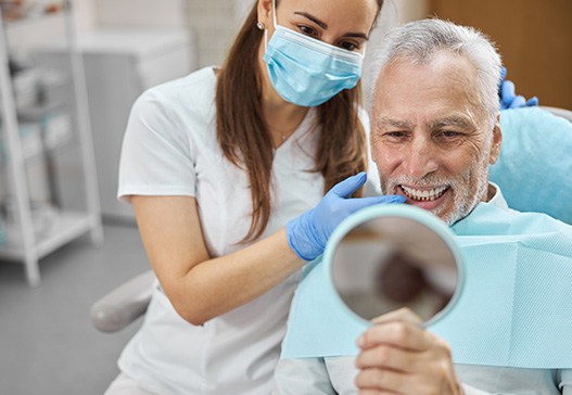 An older man admiring his newly-placed dental implants