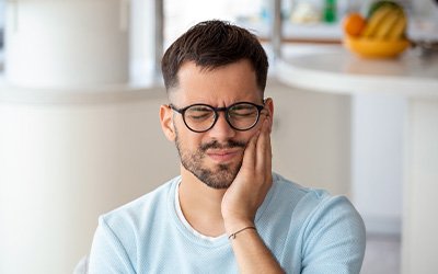 A young man suffering from a toothache after dental implant placement