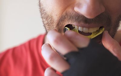 Man putting on yellow and black mouthguard